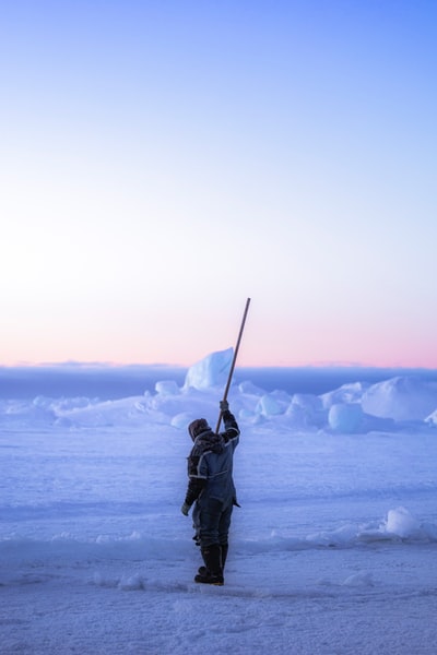 人黑棉袄控股黑贴在冰雪覆盖的地面白天
